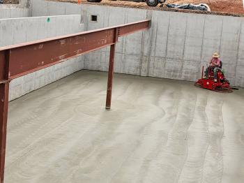 top view of a ride on power trowel finishing concrete slab in a house basement