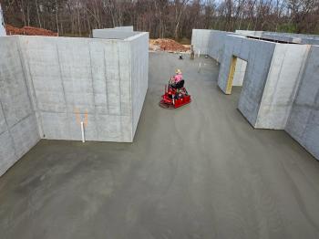 top view of a ride on power trowel finishing concrete slab in a house basement